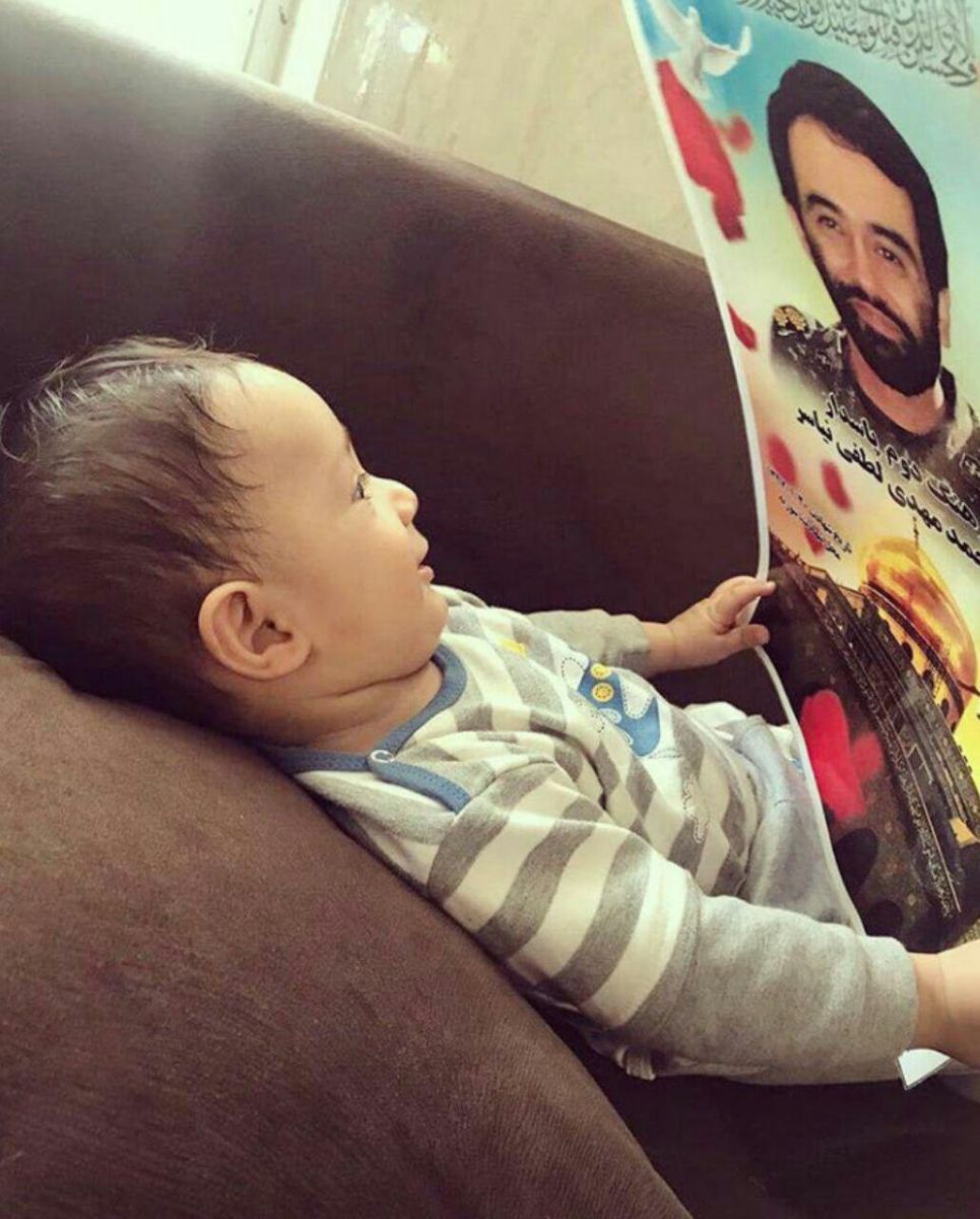 فرزند خردسال شهید در حال نظاره عکس پدر + عکس