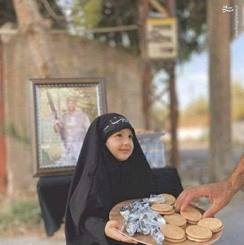 دختری که با قاب عکس پدر شهیدش به زائران خدمت می‌کند +عکس