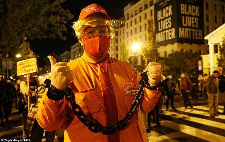 یک شهروند آمریکایی که ظاهر خود را شبیه به ترامپ کرده است دستان خود را به نشانه اعتراض و کنایه به ترامپ در حاشیه درگیری‌های خیابانی قبل از اعلام نتایج انتخابات دستبند زده است.